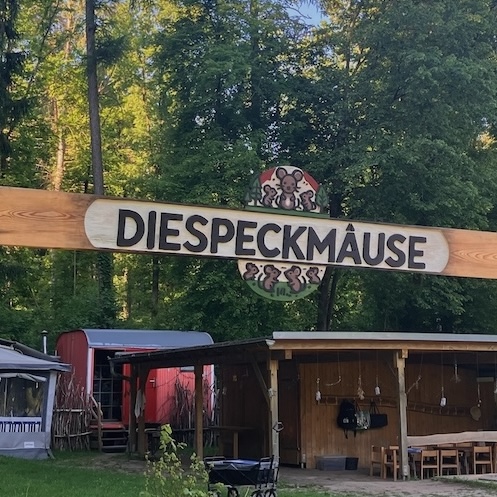 Holzschild mit Schriftzug und Logo der DIESPECKMÄUSE am Eingang